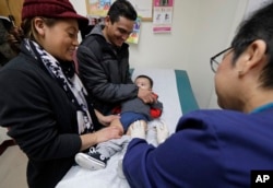 Matilde Gonzalez, left, and Cesar Calles, hold their son, Cesar Julian Calles, 10-months old, as Ana Martinez, a medical assistant at the Sea Mar Community Health Center, gives him a flu shot, Jan. 11, 2018 in Seattle.
