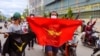 FILE - Demonstrators carry flags and display the three-finger salute during a protest against Myanmar's army ruler Min Aung Hlaing on his birthday in Mandalay, Myanmar, July 3, 2021.