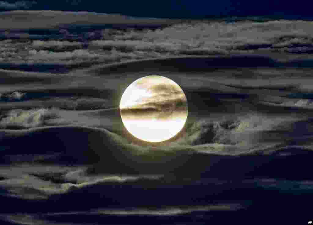 The full moon shines surrounded by clouds in the outskirts of Frankfurt, Germany.