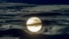 The full moon shines surrounded by clouds in the outskirts of Frankfurt, Germany.