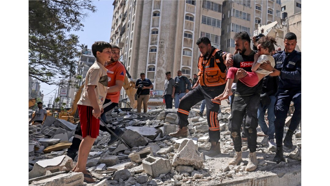 Warga Palestina mengevakuasi seorang gadis dari puing-puing bangunan yang hancur di distrik pemukiman Rimal Kota Gaza pada 16 Mei 2021, menyusul pemboman besar-besaran Israel di daerah kantong yang dikuasai Hamas. (Foto: AFP)