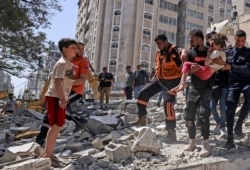 Warga Palestina mengevakuasi seorang gadis dari puing-puing bangunan yang hancur di distrik pemukiman Rimal Kota Gaza pada 16 Mei 2021, menyusul pemboman besar-besaran Israel di daerah kantong yang dikuasai Hamas. (Foto: AFP)