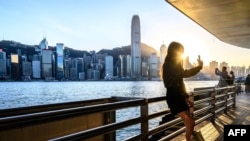 A woman takes a selfie in front of the Hong Kong skyline on November 26, 2024.