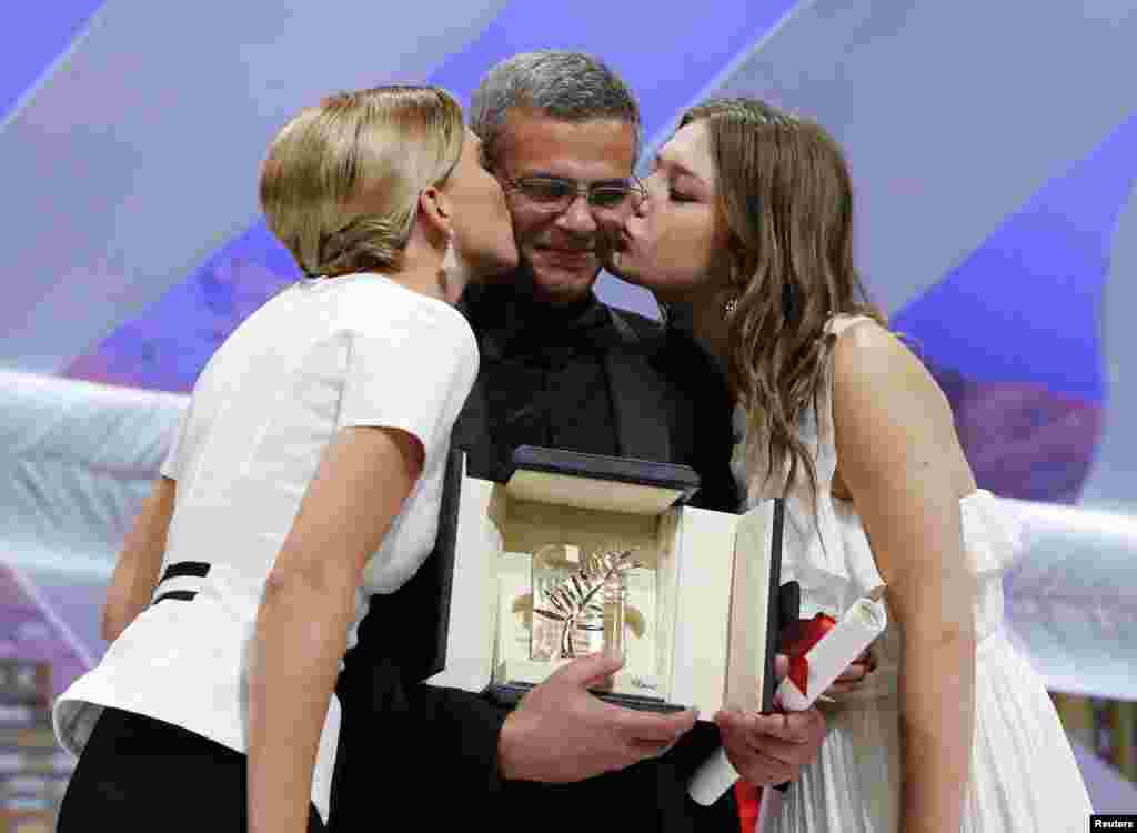 Actresses Lea Seydoux (L) and Adele Exarchopoulos (R) kiss director Abdellatif Kechiche after receiving the Palme d'Or award for the film "La Vie D'Adele" during the closing ceremony of the 66th Cannes Film Festival in Cannes, May 26, 2013.