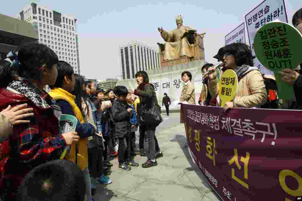 An elementary school teacher orders her students to leave as they watch South Korean housewives denounce annual South Korean-U.S. military exercises, near the U.S. Embassy in Seoul, April 8, 2013. 