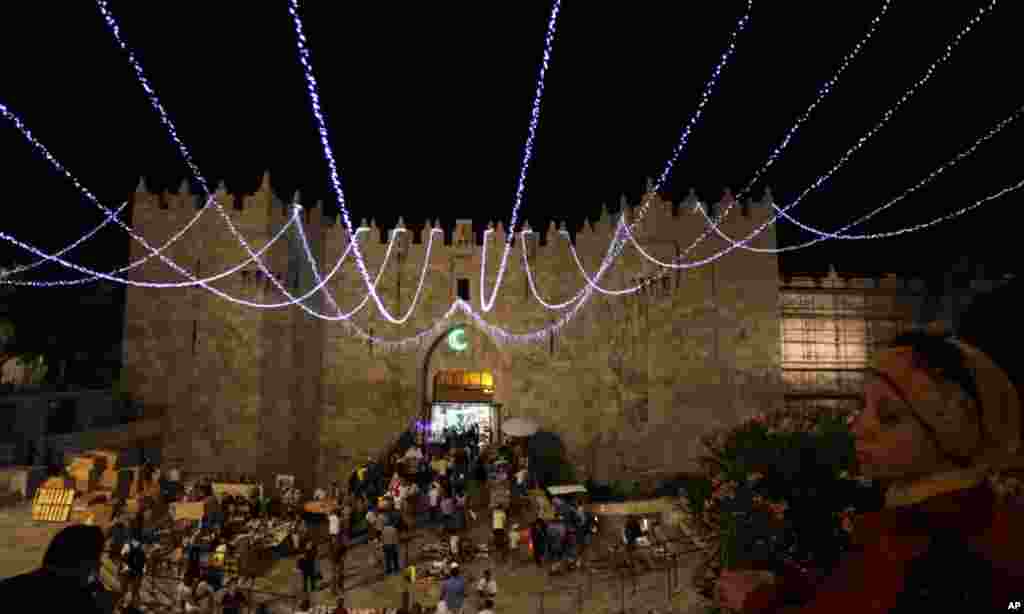 A Palestinian woman stands under decorations for the upcoming holy month of Ramadan near Damascus Gate in Jerusalem's Old City July 31, 2011. Muslims around the world abstain from eating, drinking and conducting sexual relations from sunrise to sunset dur