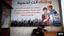 A Palestinian boy sits under a poster hung by Hamas authorities, on the Gaza side of the border crossing with Israel's Erez crossing, in Beit Hanun in the north of the Gaza Strip, May 12, 2015. 