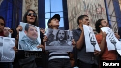 FILE - Protesters hold pictures during a protest in support of imprisoned activists at a Cairo jail.