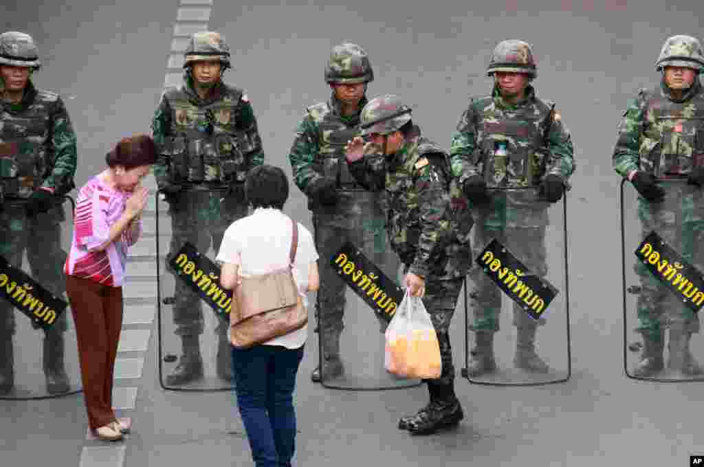 Well-wishers hand cold drinks to Thai soldiers securing the area to prevent an anti-coup demonstration at Victory Monument in Bangkok, Thailand.