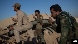 Popular Mobilization Unit fighters talk on the radio as they watch Islamic State positions in the airport of Tal Afar, west of Mosul, Iraq, Nov. 20, 2016.