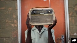 FILE - Ngwiza Khumbulani Moyo, a vintage collector, holds an old radio set outside his home in Bulawayo, Zimbabwe, Feb. 15, 2023.