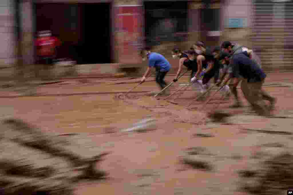 People clear mud from a street in an area affected by floods in Catarroja, Spain.