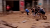 People clear mud from a street in an area affected by floods in Catarroja, Spain.