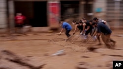 FILE - Warga membersihkan lumpur dari jalan di daerah yang terkena banjir di Catarroja, Spanyol, 4 November 2024. Bencana pada 29 Oktober itu menandai banjir paling mematikan di negara itu dalam beberapa dekade. 