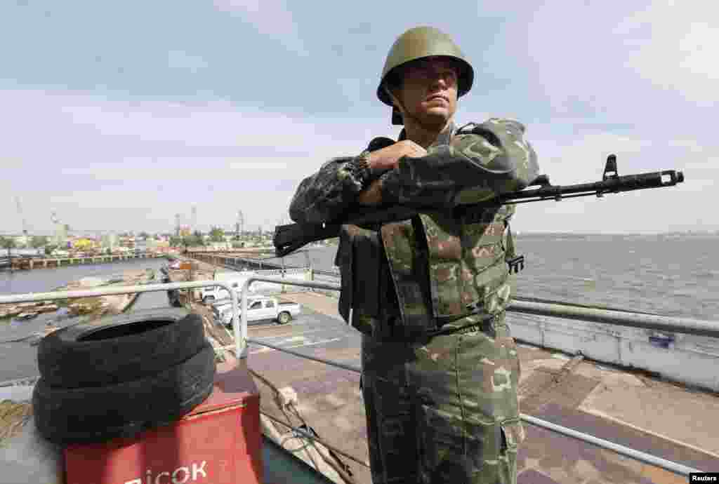 A Ukrainian serviceman stands guard on a floating coast guard post at a base in the seaport of Mariupol, Sept. 4, 2014.  