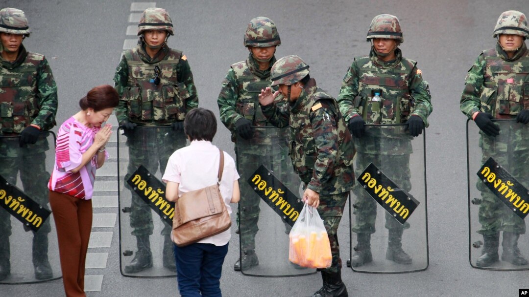 Warga lokal menyerahkan minuman dingin kepada tentara yang berjaga-jaga mencegah demonstrasi anti kudeta di Monumen Kemenangan, di Bangkok, Thailand, 29/5/2014. 