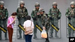 Warga lokal menyerahkan minuman dingin kepada tentara yang berjaga-jaga mencegah demonstrasi anti kudeta di Monumen Kemenangan, di Bangkok, Thailand, 29/5/2014. 