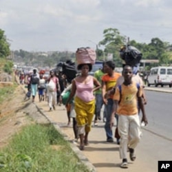Residents of Abobo district, a suburb of Abidjan, flee the quarter carrying their luggage on their heads on February 25, 2011