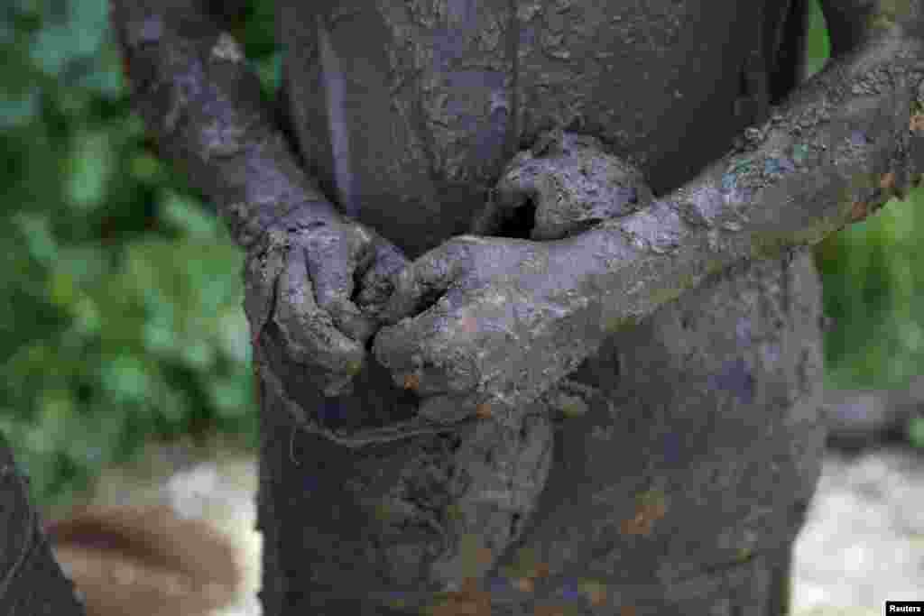 An Israeli teenager holds his muddy shoe after participating in an annual combat fitness training competition, as part of his preparations ahead of his compulsory army service, near Kibbutz Yakum, central Israel.