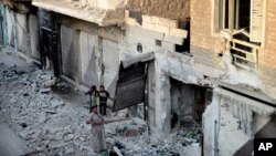 In this citizen journalism image taken on Saturday, July 28, 2012 and provided by Edlib News Network ENN, a Syrian family stand in the rubble of destroyed houses in Maarat al-Numaan on the eastern edge of Idlib province, northern Syria. 