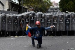 مردی در برابر پلیس که مانع یک راهپیمایی به دعوت خوان گوایدو، رهبر مخالفان، در کاراکاس در ونزوئلا، شده زانو زده است. ۱۰ مارس ۲۰۲۰