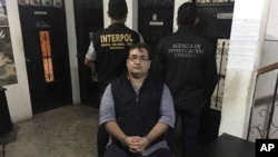 In this photo released by the Guatemala National Civil Police (PNC), Mexico's former Veracruz state Gov. Javier Duarte poses for photos escorted by an agent of the Interpol office in Guatemala (left) and a Mexico federal agent at a court room in Panajachel, Guatemala, April 15, 2017.