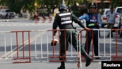 A riot police officer, left, enters a blocked street near the Supreme Court where former party leader Kem Sokha is to appear, in Phnom Penh, Cambodia, Aug. 22, 2018. 