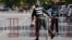 A riot police officer, left, enters a blocked street near the Supreme Court where former party leader Kem Sokha is to appear, in Phnom Penh, Cambodia, Aug. 22, 2018. 