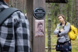 FILE - People visit the Sandarmokh memorial site, Aug. 5, 2018, located in a pine forest in Russia's Karelia region, where mass graves from the period of Joseph Stalin's purges have been found.