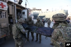 British soldiers carry the dead body of a victim in an attack near Spanish Embassy in Kabul, Afghanistan, Dec. 12, 2015.