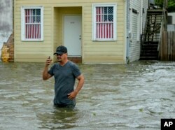 Barry Williams habla con un amigo por su celular mientras camina a través de la marejada que dejó la tormenta desde Lake Pontchartrain en Lakeshore Drive en Mandeville, Luisiana, mientras el huracán Barry se acercaba el sábado 13 de julio de 2019.