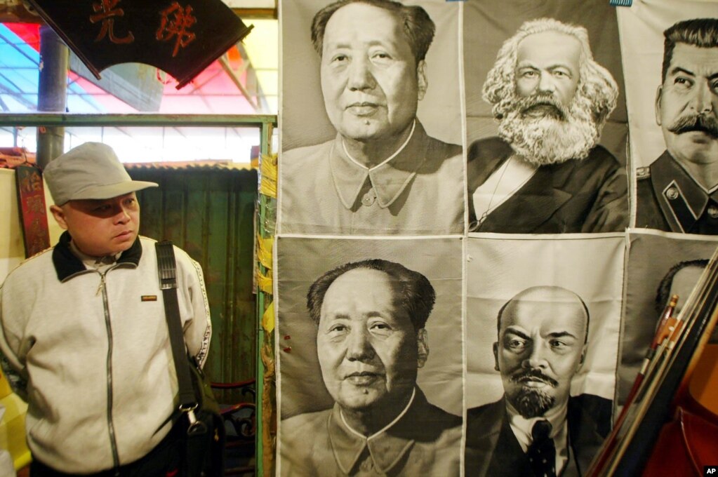 一路人观看在北京一市场里悬挂的共产主义领袖像。(photo:VOA)