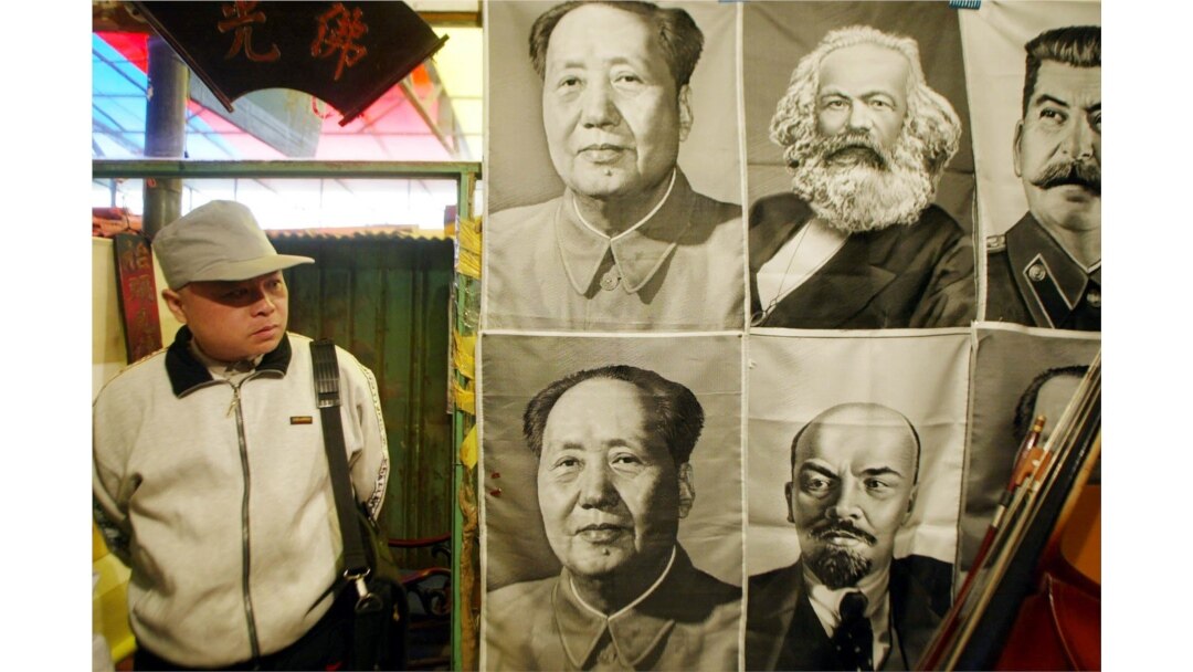 一路人观看在北京一市场里悬挂的共产主义领袖像。