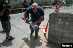 An Israeli police explosives expert carries the remains of a rocket that landed in Ashkelon, Israel, July 13, 2014.