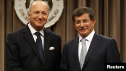 Turkish Foreign Minister Ahmet Davutoglu (R) and his French counterpart Laurent Fabius shake hands after a news conference in Ankara August 17, 2012.