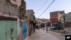 People walk past buildings that were affected by the 2023 earthquake in the town of Amizmiz, outside Marrakech, Morocco, Sept. 4, 2024.