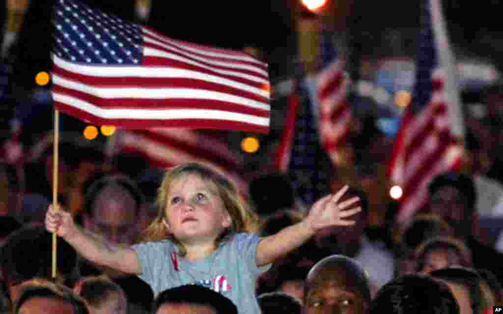 Four-year-old Alana Milawski waves an American flag as she sits on her father Craig Milawksi's shoulders during a candlelight vigil, held to honor those killed in terrorist attacks in New York and Washington, in Las Vegas.