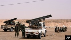 Libyan rebels gather around armed vehicles at Ajdabiya's western gate after rebels re-controlled the area, on April 17, 2011