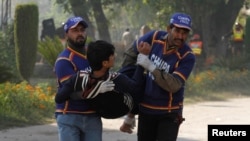 Rescue workers assist an injured student from the shooting at Directorate of Agriculture Institute in Peshawar, Pakistan, Dec. 1, 2017. 
