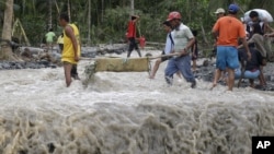 Residents cross a river with the body of a child after retrieving it from the flash flood-hit village of Andap, in New Bataan township, Compostela Valley in southern Philippines, December 5, 2012.