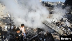 Smoke rises as Palestinians stand atop the rubble of a house, which witnesses said was destroyed in an Israeli air strike, in Rafah in the southern Gaza Strip August 20, 2014. Hamas militants in the Gaza Strip fired rockets at Israel for a second day on W