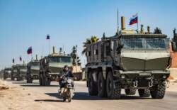 FILE - Russian military vehicles drive in a convoy from the town of Tal Tamr to Qamishli airport, March 9, 2020.