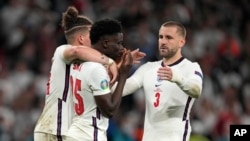 England's Bukayo Saka is comforted after he missed to score the last penalty during the penalty shootout of the Euro 2020 soccer championship final between England and Italy at Wembley stadium in London, July 11, 2021.