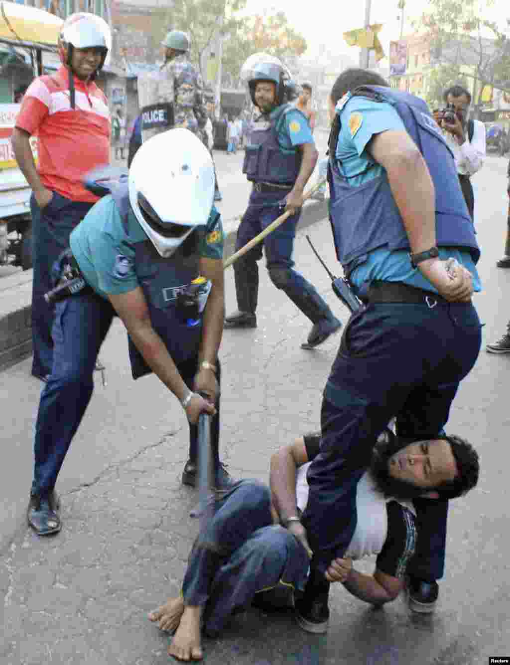 Seorang polisi memukul aktivis Jamaat-e-Islami, partai Islam terbesar di Bangladesh, dengan tongkat saat terjadi bentrokan di Jatrabari, Dhaka.