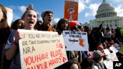 Students hold up their signs during a rally asking for gun control outside of the U.S. Capitol building, in March 14, 2018, in Washington. 