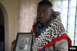 Chief Zanomthetho Mtirara poses with his leopard skin and a young picture of his adoptive "grandfather" Nelson Mandela, who was taken in by the Thembu royal family at the age of 9 when his father died. (Hannah McNeish/VOA)