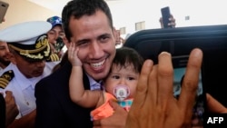 Venezuelan opposition leader and self-proclaimed acting president Juan Guaido (C) poses for a picture with a baby before leaving his hotel in Salinas, Ecuador, March 3, 2019.
