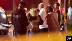People comfort each other as they stand near the scene, Nov. 8, 2018, in Thousand Oaks, Calif. where a gunman opened fire Wednesday inside a country dance bar crowded with hundreds of people.