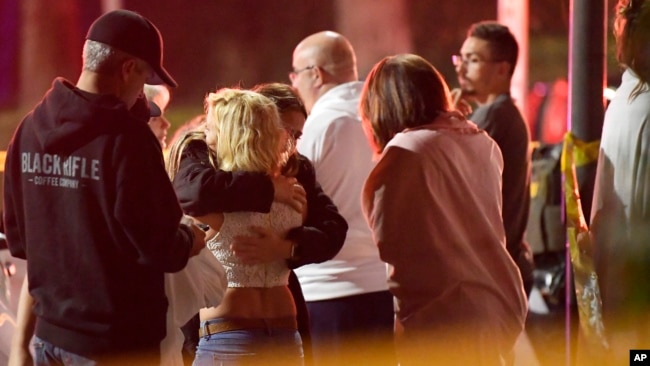 People comfort each other as they stand near the scene, Nov. 8, 2018, in Thousand Oaks, Calif. where a gunman opened fire Wednesday inside a country dance bar crowded with hundreds of people.