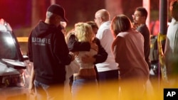 People comfort each other after a gunman opened fire Wednesday inside a country dance bar crowded with hundreds of people.